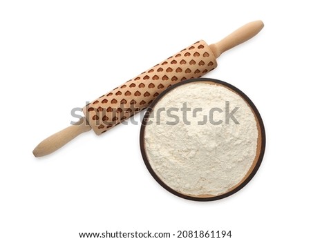 Wooden rolling pin and bowl with flour on white background, top view
