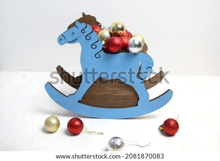 Wooden rocking horse with christmas toys on a white background