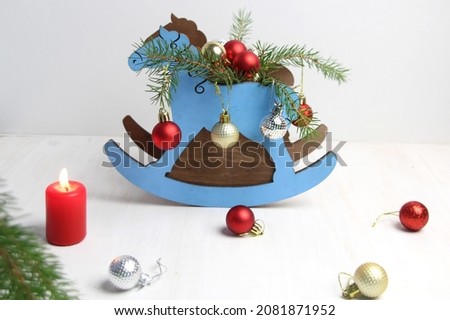 Wooden rocking horse with christmas toys, burning candle, fir tree  on a white background