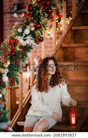 A beautiful girl portrait in a Christmas interior. Christmas tree, decorated fireplace, lots of gifts, Christmas theme. Cozy atmosphere.