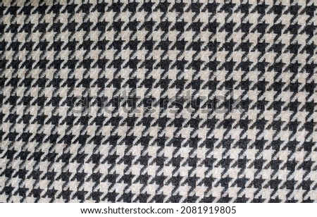 A fragment of dense fabric with small geometric patterns in black and white.