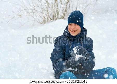 a boy plays snowballs outside, beautiful winter weather and white snow around
