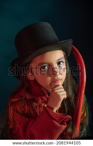 girl dressed as nutcracker with red coat fringes and colorful bokeh lights, hat and theatrical makeup