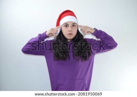 Girl in red christmas hat poses in studio