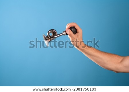 Attention, vintage bicycle horn, loud signal to attract attention. Horn in a man's hand, blue background. Royalty-Free Stock Photo #2081950183
