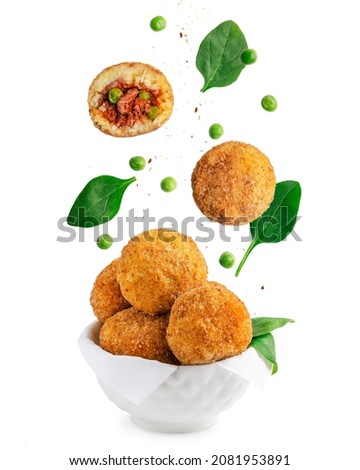 Levitation of Arancini Italian rice balls coated with bread crumb, deep fried and stuffed with minced beef meat with green peas, spinach and tomato sauce served in bowl isolated on white background Royalty-Free Stock Photo #2081953891