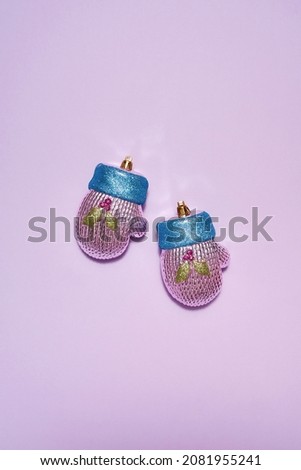 Pair of colorful christmas baubles in form of winter glove isolated on purple background. Concept of Xmas and New Year. Beautiful decorations for winter events, holidays and greetings. Copy space