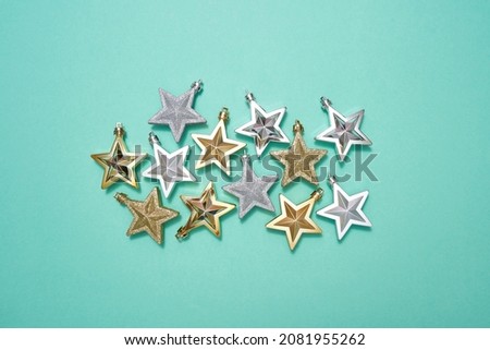 Top view of set of golden and silver christmas baubles in form of star isolated on green background. Concept of Christmas and New Year. Beautiful decorations for winter events and holidays. Copy space