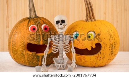 Halloween Carved Pumpkins with Candy Eyes Silly Faces and Skeleton on a Rustic Background. Fun and Scary Holiday Event