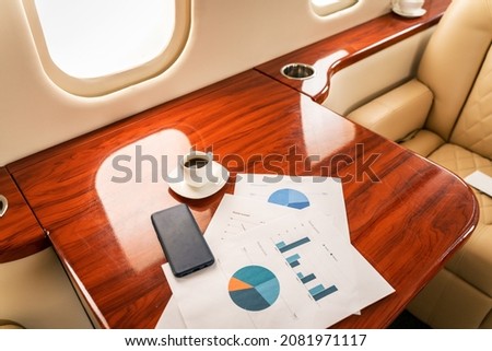 Private jet, data chart and smartphone on table