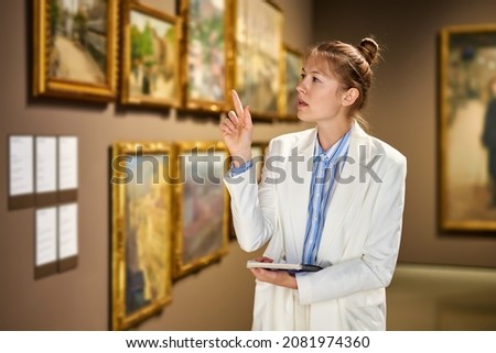 Woman visitor standing near pictures at museum of arts