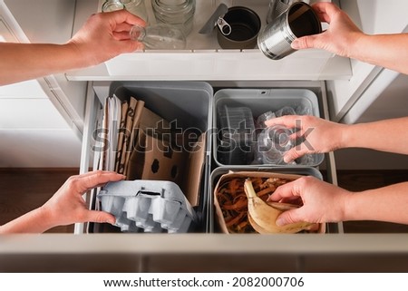 Hands putting segregated household garbage to separate trash bins - plastic, cardboard, bio, metal and glass. Royalty-Free Stock Photo #2082000706