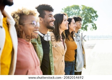 Side view of united multiracial people hugging each other in cooperation - Group of happy young friends supporting together in line - Cooperation, teamwork and unity concept Royalty-Free Stock Photo #2082014692