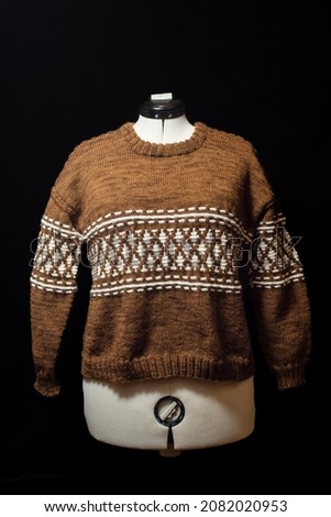 Hand knitted brown and white sweater on a white mannequin.