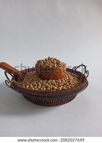 Close view and Selective Focus on Fresh soybean in brown wicker basket and small wooden bowl and spoon.  Isolated on white Background. Soft Blurry Image. Raw Food. Protein. Hairy plant. Nature. Rural.