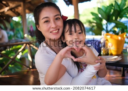 family Mother and daughter happy and smiling together make hand to heart sign