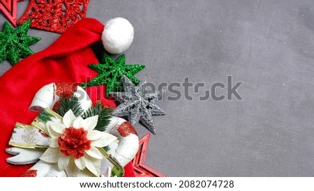 Christmas hat and some Christmas baubles on a gray background, which gives beauty in a unique pattern. Christmas and New Year concept. Negative space, flat lay, top view. Christmas template.