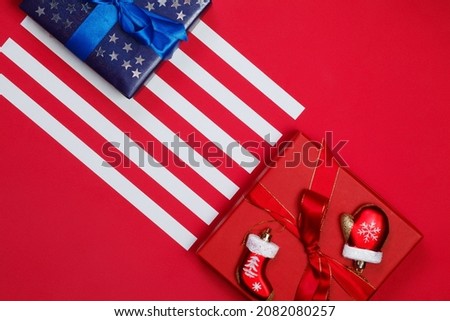 American flag composition with blue gift decorated with glittering stars and christmas tree decorations on red background. Merry christmas and happy new year concept.

