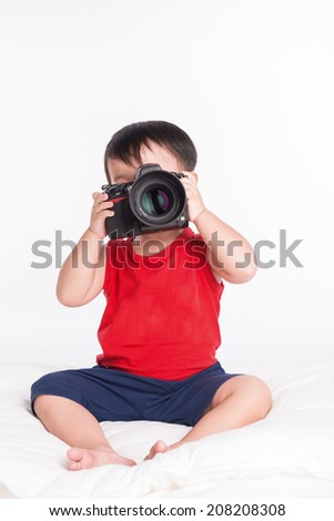 Baby boy playing with professional camera. Taking photo. Isolated on white background