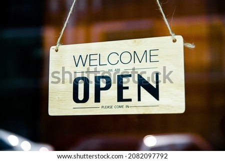 Welcome we are open signage in the front door of shop and restuarant after covid-19 lockdown on the blurred background.