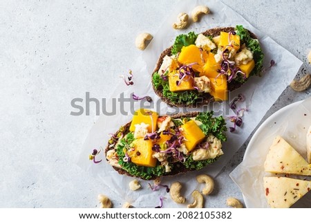 Vegan toasts with cashew cheese, mango and kale, top view, copy space. Alternative plant-based food, healthy dairy-free diet concept. Royalty-Free Stock Photo #2082105382
