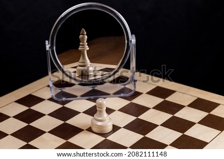 A chess pawn looks in the mirror and sees himself as a king. Often in life, things and people are not what they seem. Trust yourself, the concept of self-confidence Royalty-Free Stock Photo #2082111148