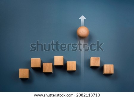 Leadership, business success, unique, difference, challenge, and motivation concepts. Wooden sphere rolling faster leading with rising arrow and following with wood cube blocks on blue background. Royalty-Free Stock Photo #2082113710