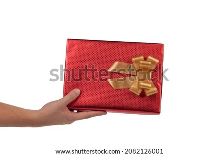Red gift box with golden bow in hand. Isolated over white background. Close-up.