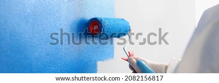 Repairman painting white wall in apartment blue using roller closeup Royalty-Free Stock Photo #2082156817