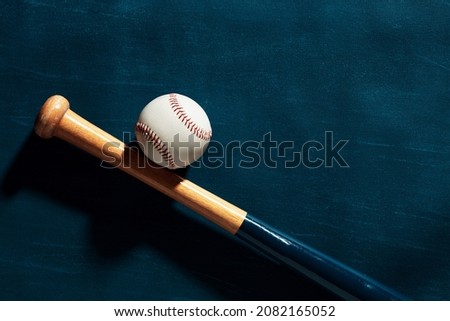 Blue wooden baseball bat and a baseball ball on blue background with copy space.