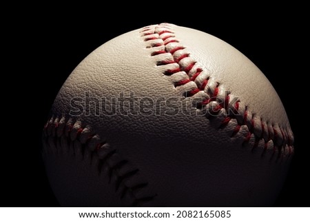 Macro close-up baseball ball isolated on black background.