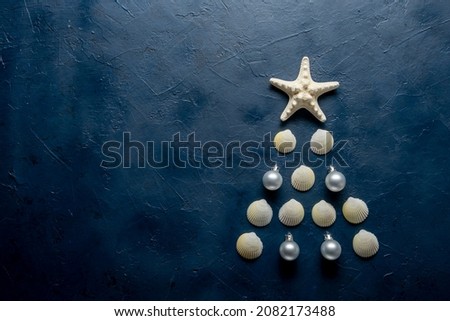 Christmas tree from sea shells and starfish on blue background, top view