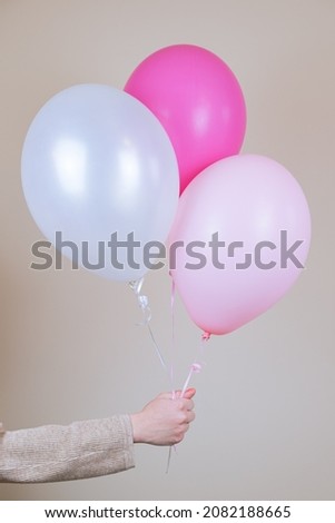 A female hand holds a three helium balloon. The concept of holiday decorations, accessories for the children's holiday. Vertical image