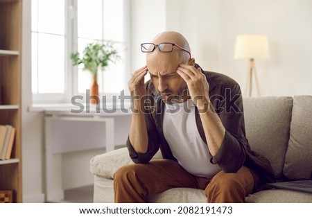 Man starts to realise. Confused thinker sitting on sofa with laptop computer at home, thinking, trying to understand situation, find answer, remember difficult word, analyze or resolve complex problem Royalty-Free Stock Photo #2082191473