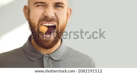 Confident, charismatic, handsome man winks his eye and cracks a hard nut. Close up head shot of a young ginger guy demonstrating his healthy teeth and trying to crack a walnut. Dental health concept Royalty-Free Stock Photo #2082191512