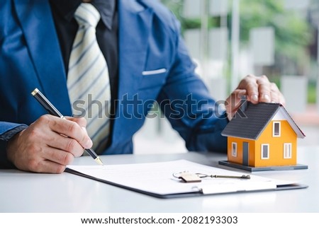 Man Signing A Contract When Buying A New House after agreeing to make a home purchase agreement and make a loan agreement. Discussion with a real estate agent 

