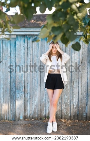 Portrait of a strolling girl near a shabby fence.