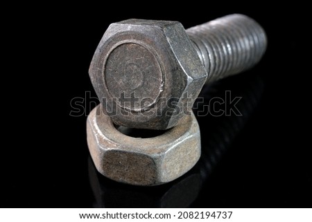 Old used bolt and nut on black mirror background close-up macro photography