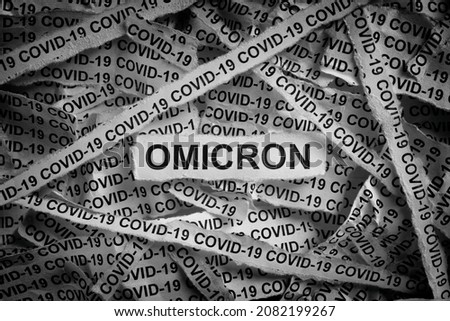 Strips of newspaper with the words Omicron and Covid-19 typed on them. Omicron variant of COVID-19. Black and white. Close up. Royalty-Free Stock Photo #2082199267
