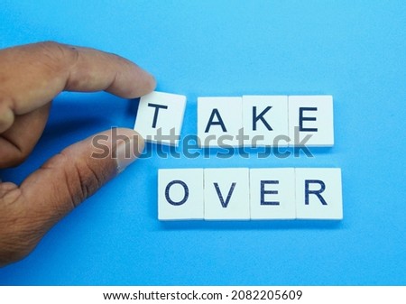 the finger holds a white square with the word take over. the concept of acquisition Royalty-Free Stock Photo #2082205609