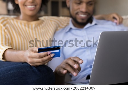 Young married couple shopping online from home, paying by credit card, making payments for purchase from virtual account, electronic wallet, paying bills, using laptop computer. Close up Royalty-Free Stock Photo #2082214009
