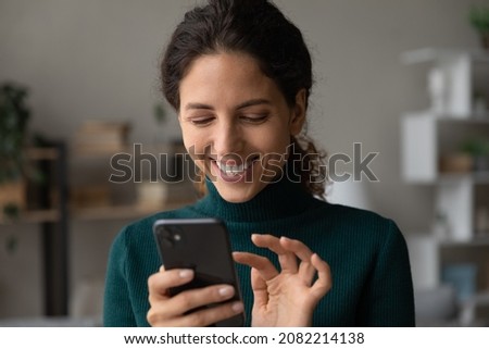 Good virtual conversation. Smiling millennial latina lady touch smartphone screen text answer on friend message scroll social media networking. Happy young female online shopper buy goods in one click Royalty-Free Stock Photo #2082214138