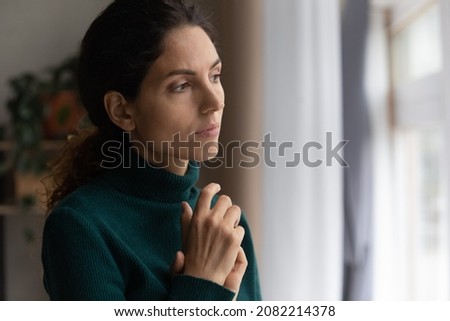 Unhappy thoughts. Worried young latin woman look at window feel lonely sad wait for boyfriend husband coming back after quarrel. Pessimistic millennial lady hide from life problems at home. Copy space Royalty-Free Stock Photo #2082214378