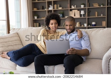 Millennial African married couple paying common bills, insurance, mortgage fees, taxes on internet, making online payments on laptop, using financial banking app on computer at home Royalty-Free Stock Photo #2082214684