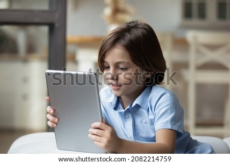 Close up lovely little boy relaxing at home alone with wireless digital tablet device. Parental control software apps, children safe usage of modern tech, cyberspace, internet, fun and leisure concept