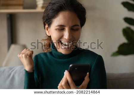 That is great. Excited amazed latina female celebrate winning mobile video game on phone. Ecstatic joyful young woman read message on cell screen about receiving money prize at social media contest Royalty-Free Stock Photo #2082214864