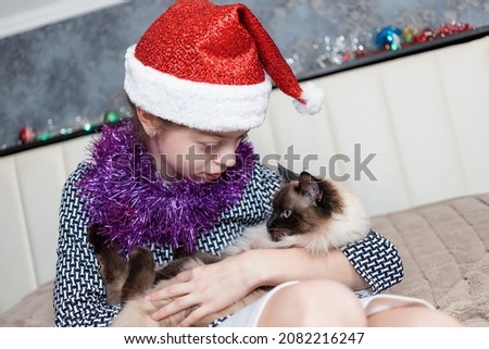 A pretty girl plays with a Siamese cat on New Year's Eve praisers