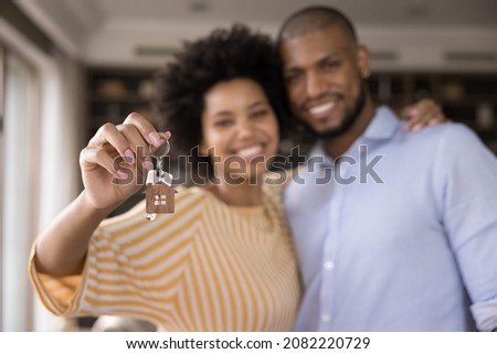 Happy Black millennial couple showing keys, smiling at camera, hugging. Husband and wife, new homeowners, tenants excited with house buying, real estate property purchase, renting apartment. Close up Royalty-Free Stock Photo #2082220729