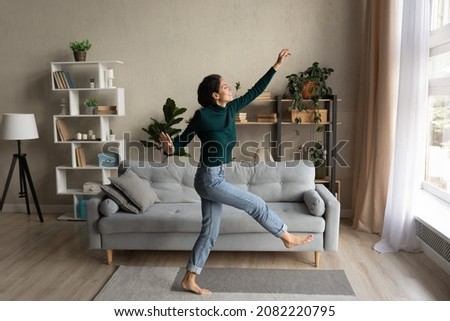 Wonderful life. Overjoyed happy millennial hispanic woman dance at modern living room in playful mood enjoy weekend leisure time. Carefree young lady having fun celebrate freedom after cleaning home Royalty-Free Stock Photo #2082220795