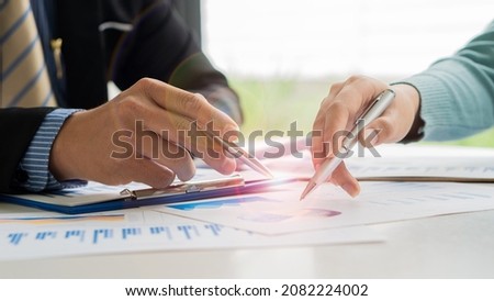 Business team discussing and planning projects using charts, holding pens and analytical papers on office table. with a laptop computer and a financial graph running in the background. business idea Royalty-Free Stock Photo #2082224002